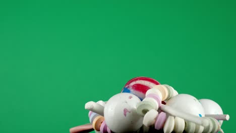 una porción de dulces variados y sabrosos, girando en una bandeja contra un fondo de estudio de color verde profundo