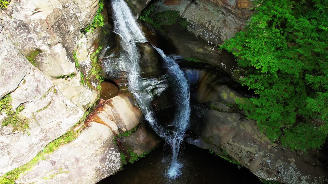 Drone lowers and pans up to reveal beautiful waterfall