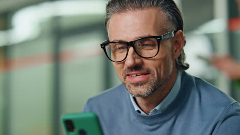 smiling businessman greeting video call in office closeup. happy man waving hand