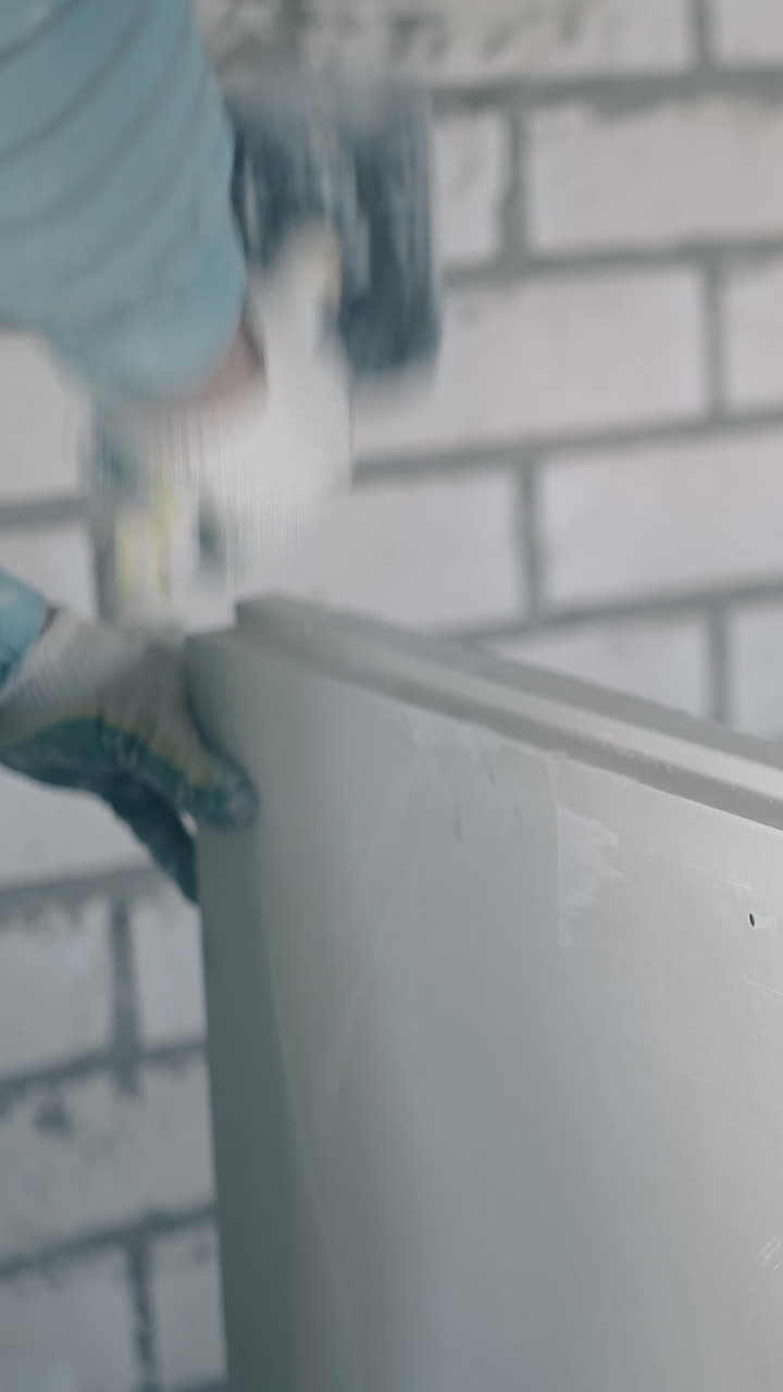 professional plasterer prepares gypsum plasterboard decorative wall and beats construction with rubber hammer closeup