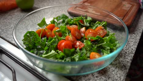 ensalada verde con tomates cherry recién cortados en un recipiente de vidrio