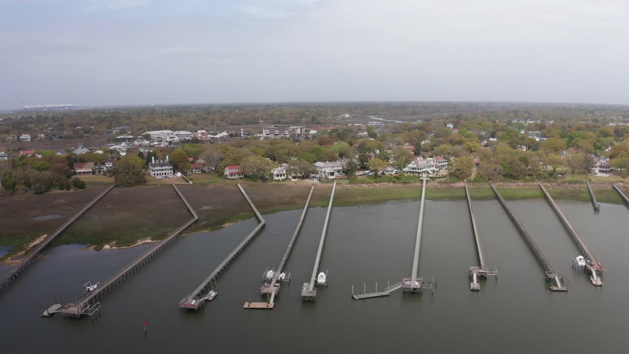 Wide aerial dolly shot of long fishing piers along Charleston Bay near historic Old Village Mount Pleasant, South Carolina