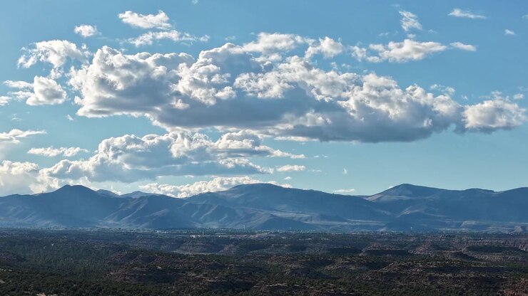 Timelapse 4K de dron que captura hermosas nubes desplazándose sobre escarpadas mesetas y picos montañosos del suroeste. Fondo cinematográfico aéreo de naturaleza con transiciones dinámicas de paisajes celestes y vistas desérticas