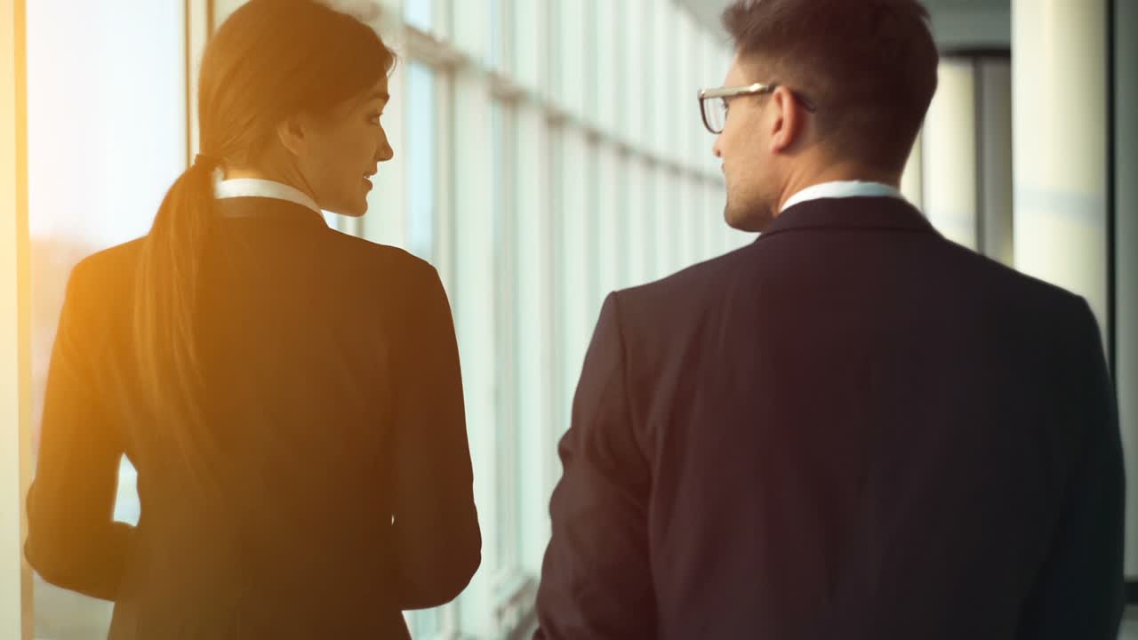 el hombre y una mujer caminando cerca de la ventana en el centro de la oficina. cámara lenta