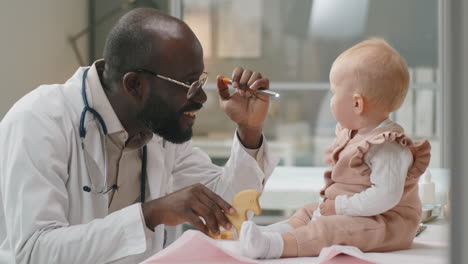 african american pediatrician giving checkup to caucasian baby girl