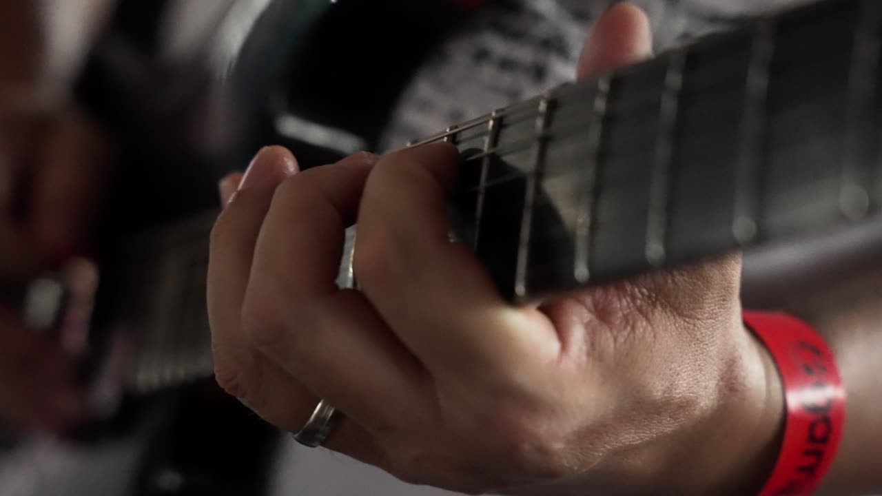Closeup of musician hand playing solo on electric guitar in slow motion