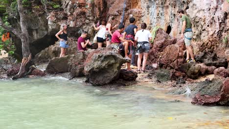 people climbing rocks by the sea in thailand