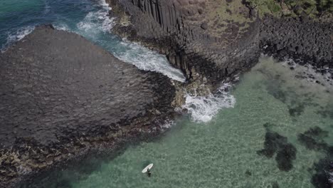 Wellen,-Die-Auf-Basaltfelsen-Am-Fingal-Head-Causeway-Mit-Surfern-Im-Klaren-Blauen-Meer-Im-Sommer-Krachen