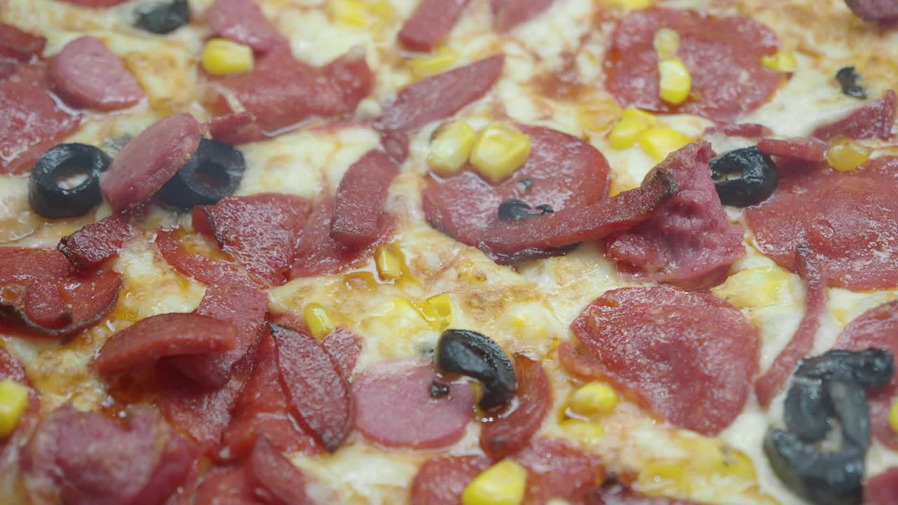 Pizza with salami, olives, corn, and cheese