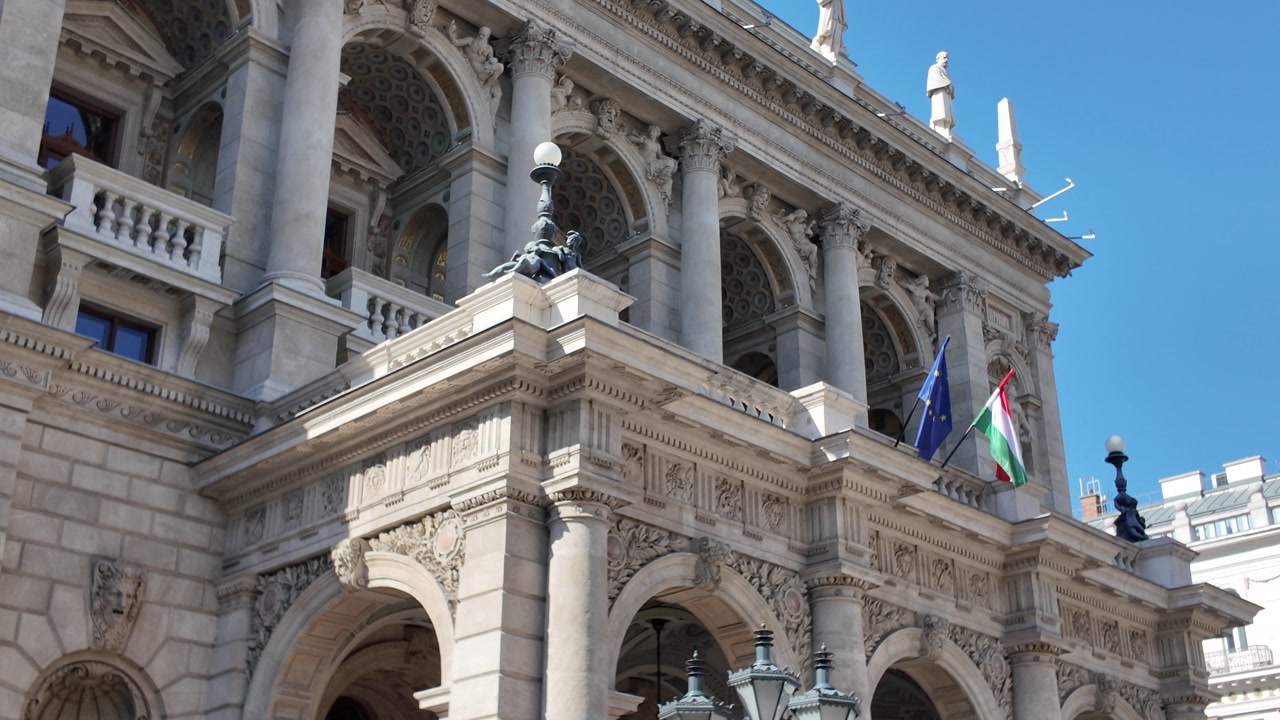Opera house front façade in Budapest, showcasing intricate arches, sculpted statues, and classical architectural details