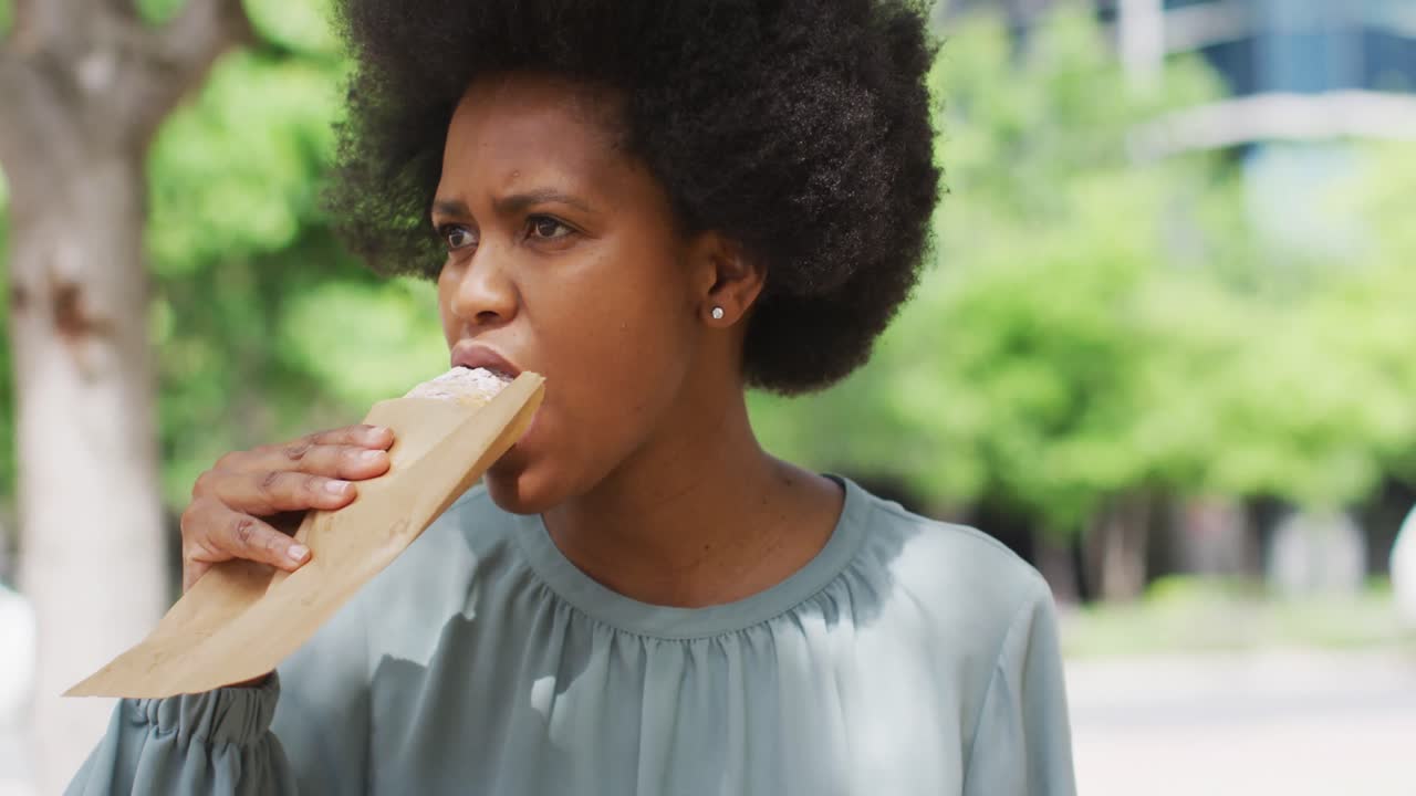 African american businesswoman eating in city