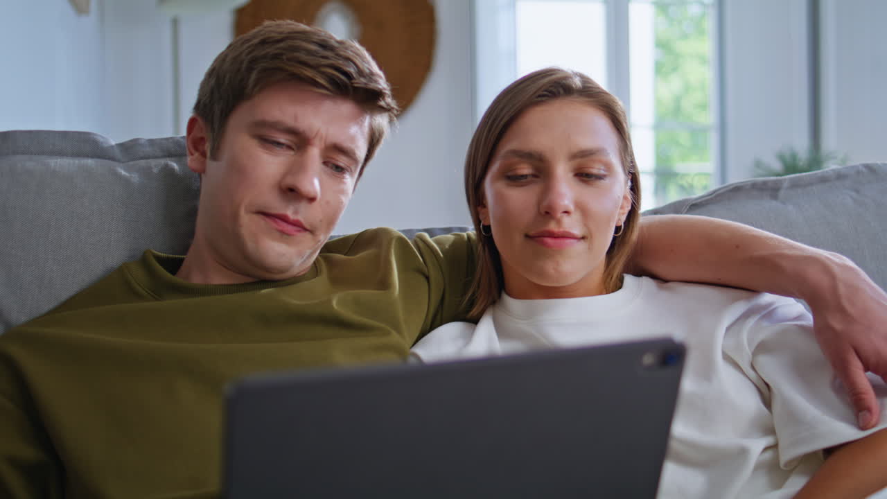 Relaxed teenagers looking tablet in house closeup. Couple spending time together