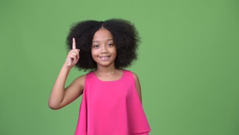 young cute african girl with afro hair pointing finger up