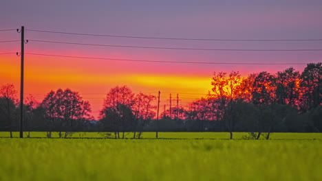 Fiery-sunset-sky-glowing-above-agriculture-fields,-telephoto-zoom-fusion-time-lapse
