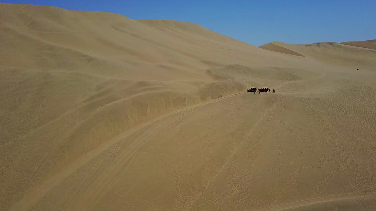 dunas de arena del desierto con personas y un buggy en huacachina, perú