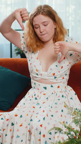 upset young woman showing thumbs down dislike bad work disapproval dissatisfied feedback at home