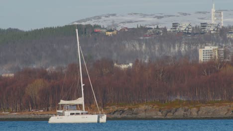 Pequeño-Barco-Blanco-Navegando-A-Lo-Largo-Del-Fiordo-En-El-Norte-De-Noruega,-Teleobjetivo-Disparado-En-Cámara-Lenta-De-60-Fps