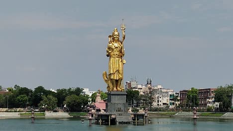 close-up view of majestic golden lord shiva statue standing tall in sursagar lake, vadodara, gujarat. sacred and iconic landmark amid urban surroundings and spiritual ambiance.