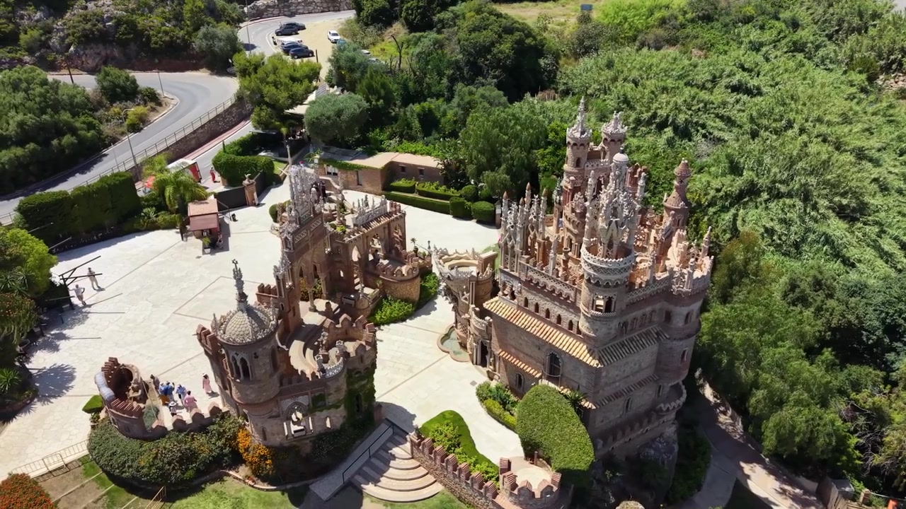 Dronebilde av Colomares slottkompleks i Benalmádena, Málaga, Spania, som fremhever dets utsmykkede tårn, gårdsplasser, dekorative arkitektur og monument dedikert til Christofer Columbus.
