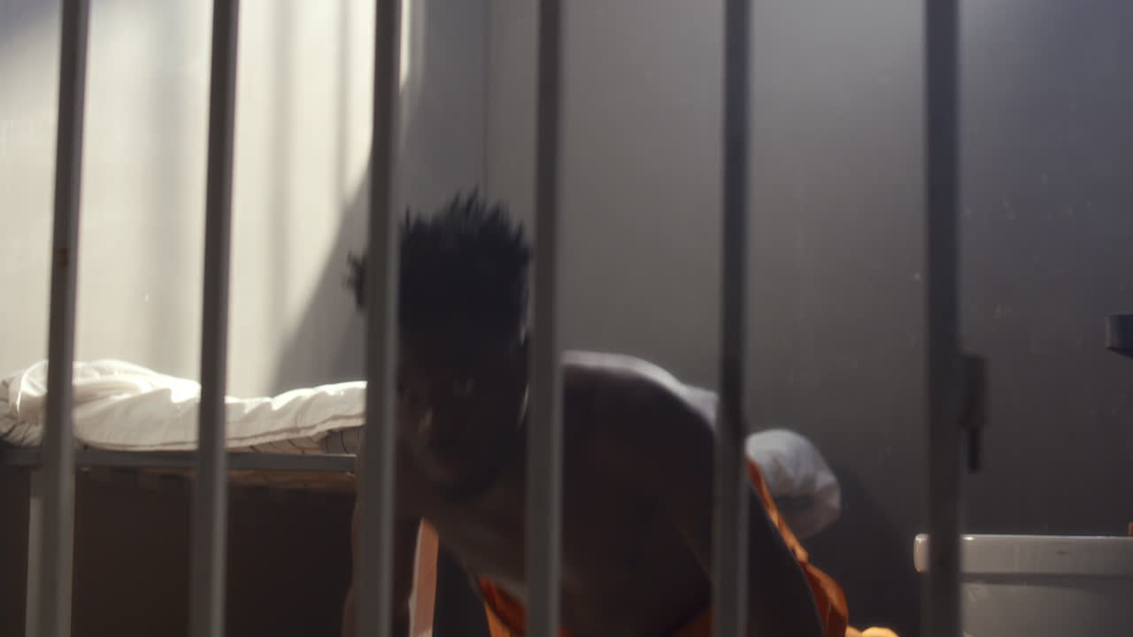 African American Inmate Performing Pushups while Training in Prison Cell