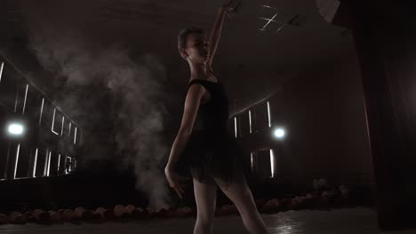 a graceful ballerina dancing ballet elements in the dark with light and smoke on the background, slow motion.