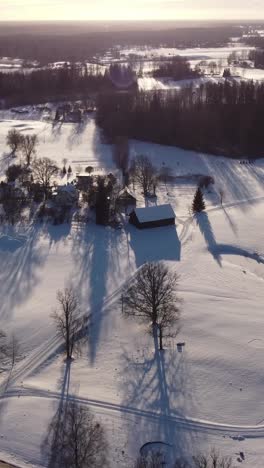 a vertical shot captures the beauty of a winter sunset over latvia, with snow-covered houses glowing in the warm light.