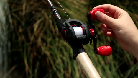 close up shot of hands reeling in a bass fishing reel