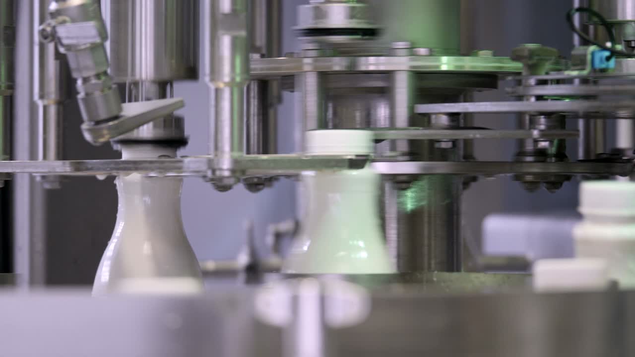 우유 생산 라인의 움직이는, 병은 우유로 채워지고 밀폐됩니다.