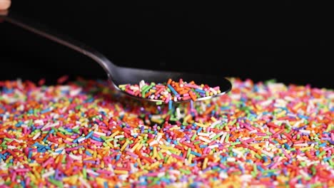 a spoon gathers colorful sprinkles from a pile