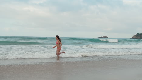 Young-woman-spending-summer-at-seaside.-Cheerful-girl-running-along-beach.