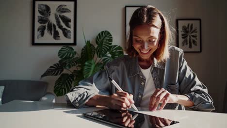 a woman smiling while writing at a desk, captured in a warm, inviting video with a low-angle shot