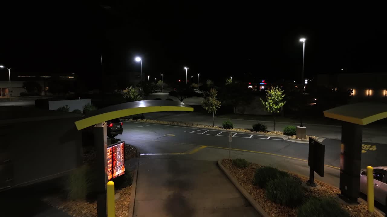 Mc Donalds Drive Thru in American town at night. Aerial establishing shot. Cars ordering burger and fries at night. Virginia, USA. Flyover shot.