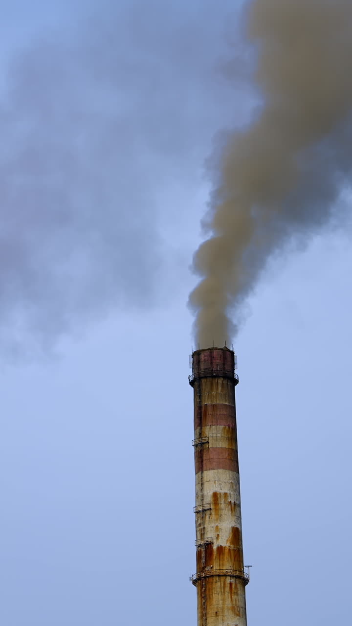 Smoke pouring from two industrial pipes. Factory cocncrete pipes pollute air with smoke. Vertical video