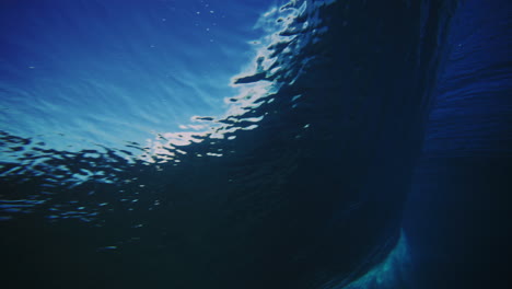 backside view of strong ocean wave as it throws powerful lip of wave forward bursting with light, underwater texture