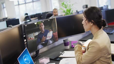 Asiatische-Geschäftsfrau-Im-Büro,-Die-Einen-Computer-Mit-Videoanruf-Und-KI-Nachrichten-Auf-Bildschirmen-Nutzt