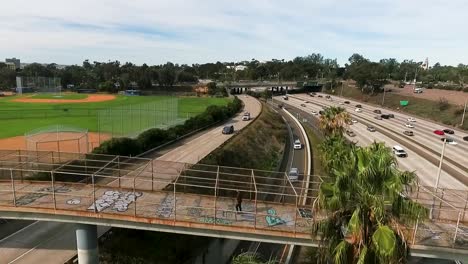 Man-walking-on-bridge-over-freeway