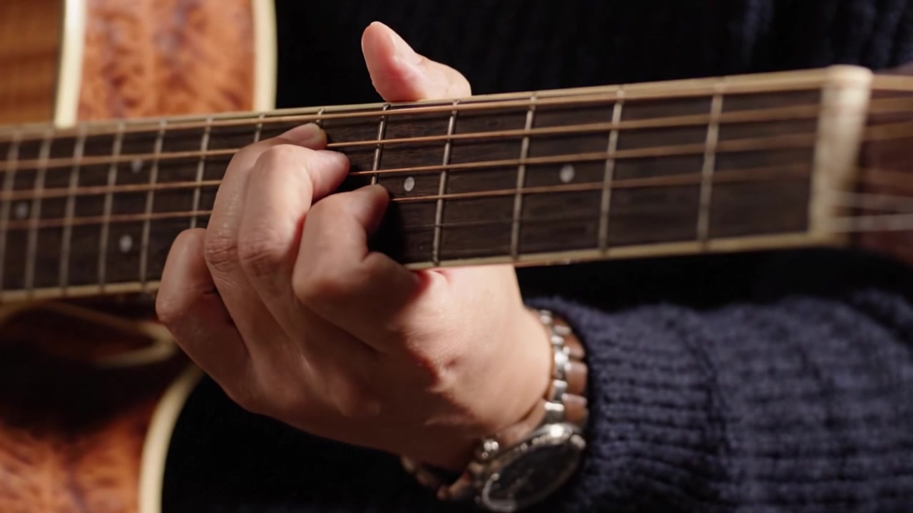 Un primo piano della mano di un chitarrista esperto che suona con maestria una chitarra acustica, mostrando l'arte e la finezza coinvolte nella manipolazione delle corde e nella progressione degli accordi.