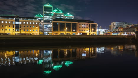 time lapse of ulster bank building illuminated at night with traffic along liffey river in dublin city in ireland