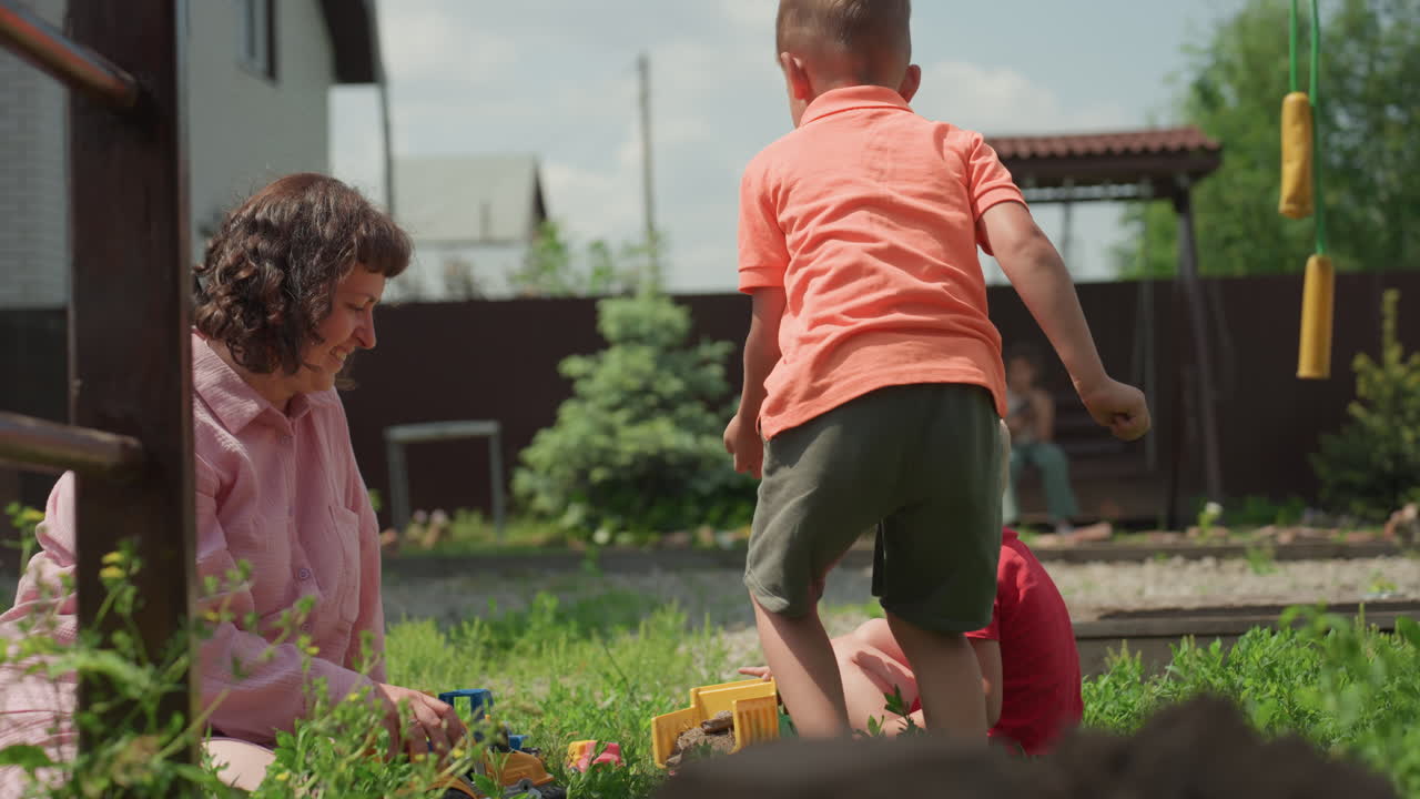 Children Playing Backyard Grass Siblings Share Toys While Caregiver Watches, Close Shots Of Hands And Movement, Cooperative Interaction, Bright Summer Light, Playful Energy And Gentle Supervision