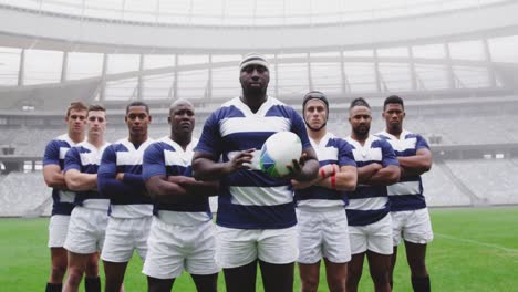 jugadores de rugby de sexo masculino de pie juntos con una pelota de rugby en el estadio 4k