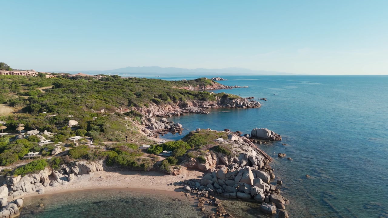 Vista aerea della costa rocciosa sarda con mare blu limpido e piccola spiaggia sabbiosa