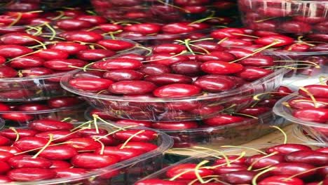 close-up of fresh red cherries in plastic containers at a market