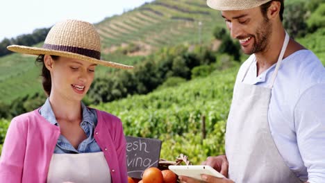 pareja usando tableta digital mientras sostiene verduras frescas