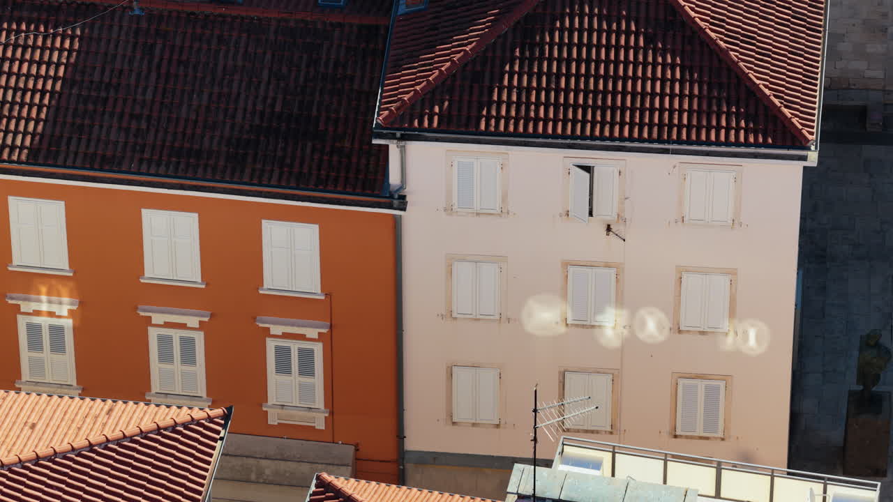 Aerial drone view of colorful Mediterranean style buildings with orange and yellow facades, white shutters, and terracotta roofs. Zadar, Croatia