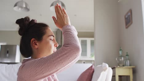 feliz mujer caucásica sentada en el sofá y meditando en la sala de estar
