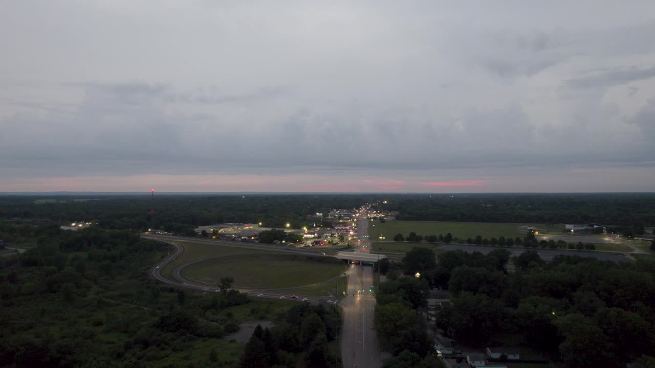 해질녘 도로 양쪽에 작은 집들이 있는 좁은 차선이 있는 고속도로에서 공중 드론이 촬영되었습니다.