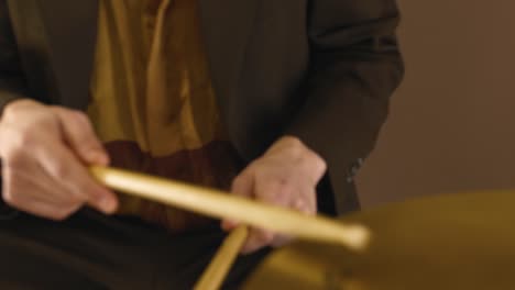 drummer beating the hi-hat cymbals and snare drum with drumsticks - extreme close up