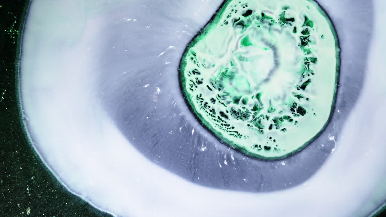 Green ink mixing close-up, creating abstract patterns and textures