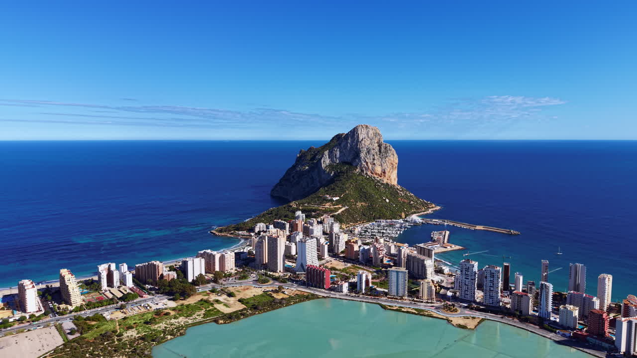 Calpe, città costiera della Spagna, con la formazione rocciosa del Peñón de Ifach che si erge sul Mar Mediterraneo, con porto turistico, grattacieli e una laguna turchese.
