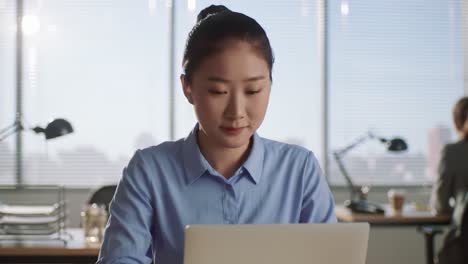 focused professional engaged in work at modern office, concentrating on laptop with natural light illuminating the workspace environment